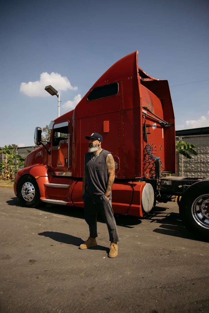 Driver standing next to his red truck at the yard